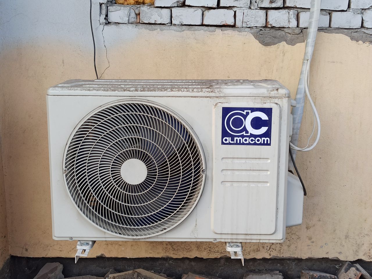 why-choose-us A well-used outdoor air conditioning unit affixed to a brick wall, showcasing urban climate control.