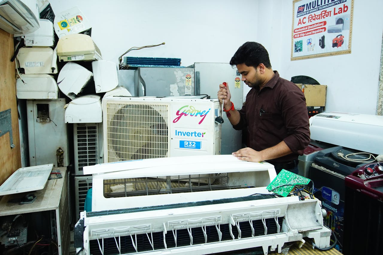 hero-img-01 Technician repairing an air conditioner unit in New Delhi workshop.